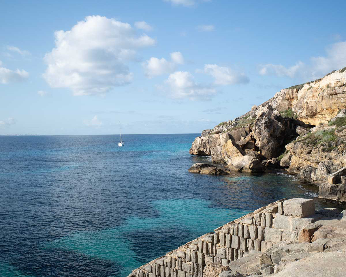 Scorcio della costa di Favignana vicino alla spiaggia del Bue Marino, con mare turchese e barca all'orizzonte