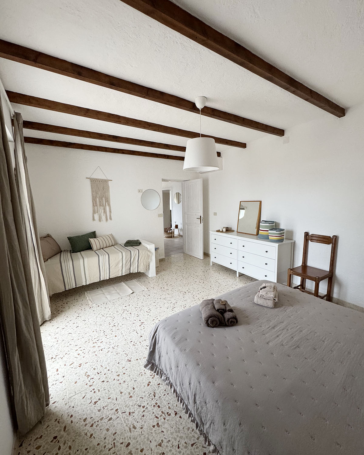 Camera tripla di Mae a Favignana con letto matrimoniale, biancheria dai toni neutri e luce calda diffusa.