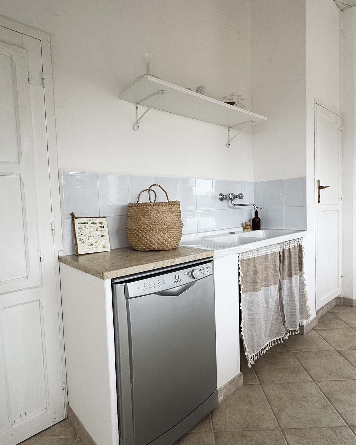 Cucinotto di Mae a Favignana con lavello, lavastoviglie, mensola a vista e dettagli in fibre naturali.