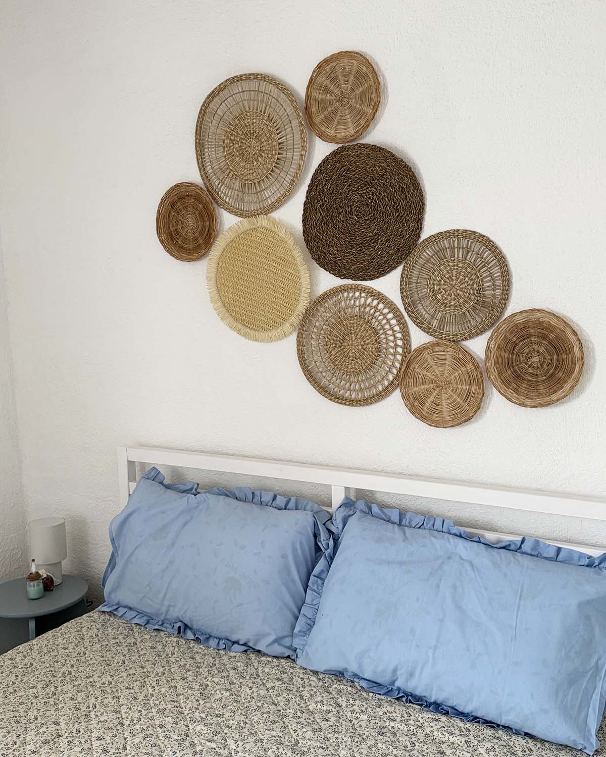 Dettaglio della camera doppia di Mae a Favignana con letto, cuscini azzurri e decorazioni intrecciate sulla parete.