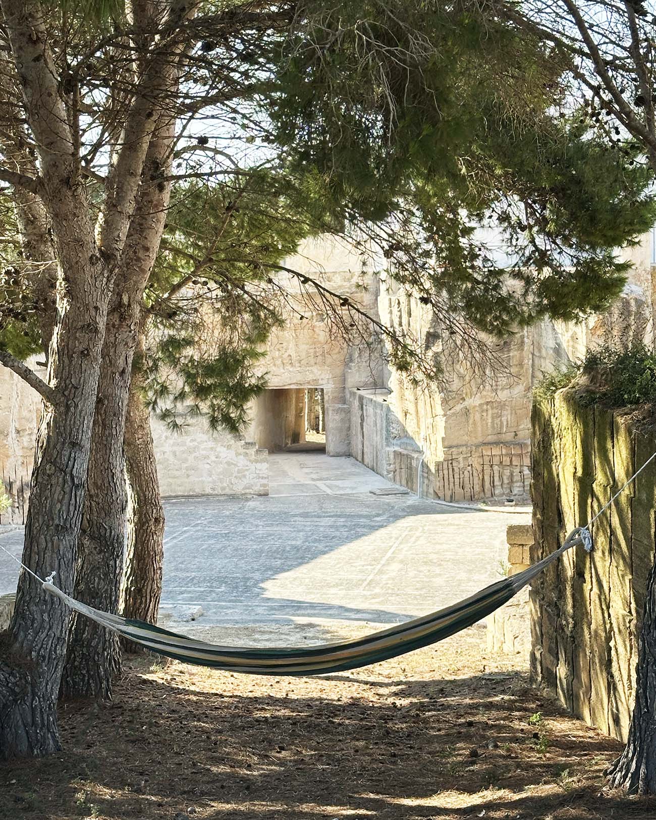 Angolo relax negli esterni di Mae a Favignana con amaca tra gli alberi, affaccio sulla cava di tufo e campo da tennis.