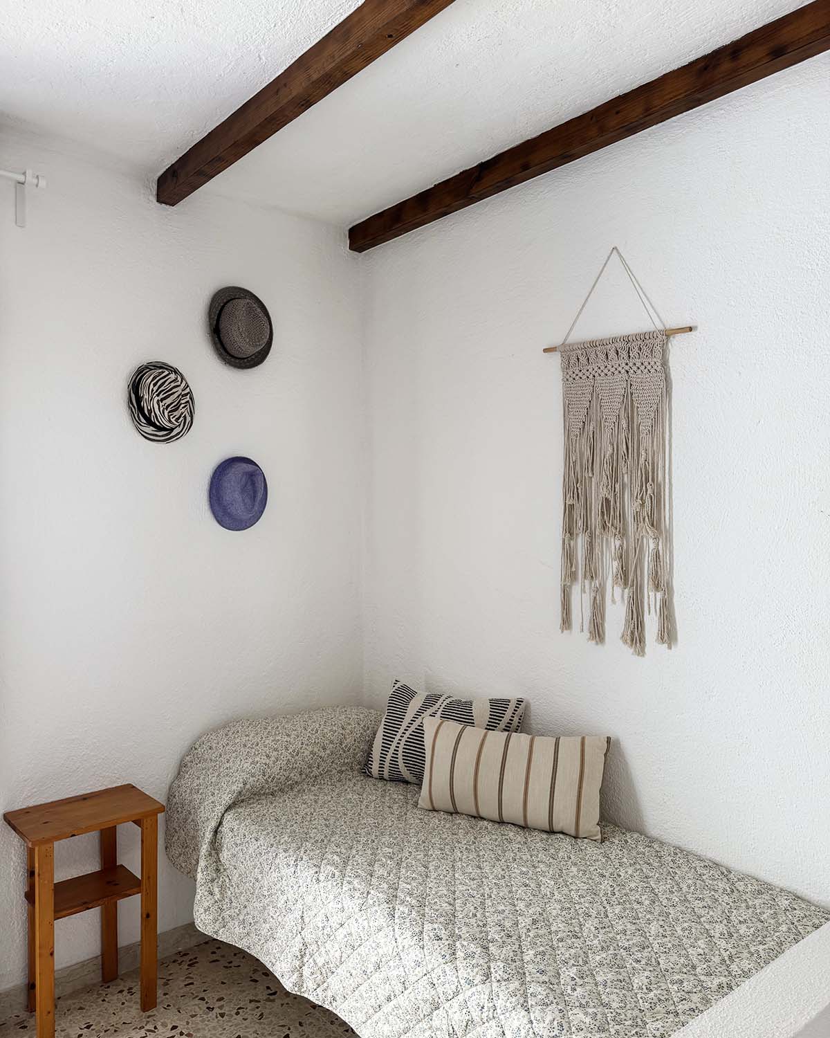 Letto singolo di Mae a Favignana con letto, cuscini decorativi, travi in legno e dettagli tessili in stile naturale.