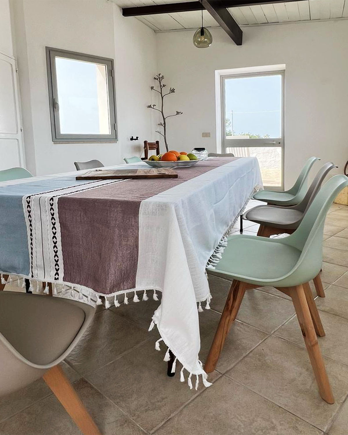 Zona pranzo di Mae a Favignana con tavolo apparecchiato, sedute moderne e luce naturale che entra dalle finestre.