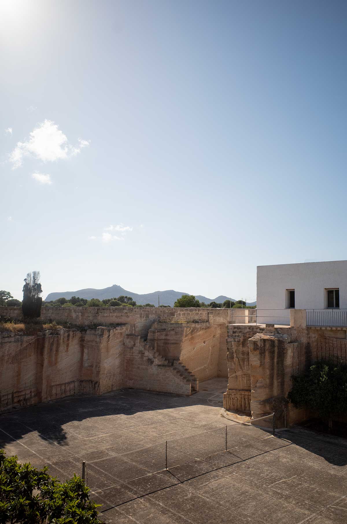 Scorcio della cava di tufo di Mae a Favignana con scale in pietra e una ragazza con cappello le attraversa