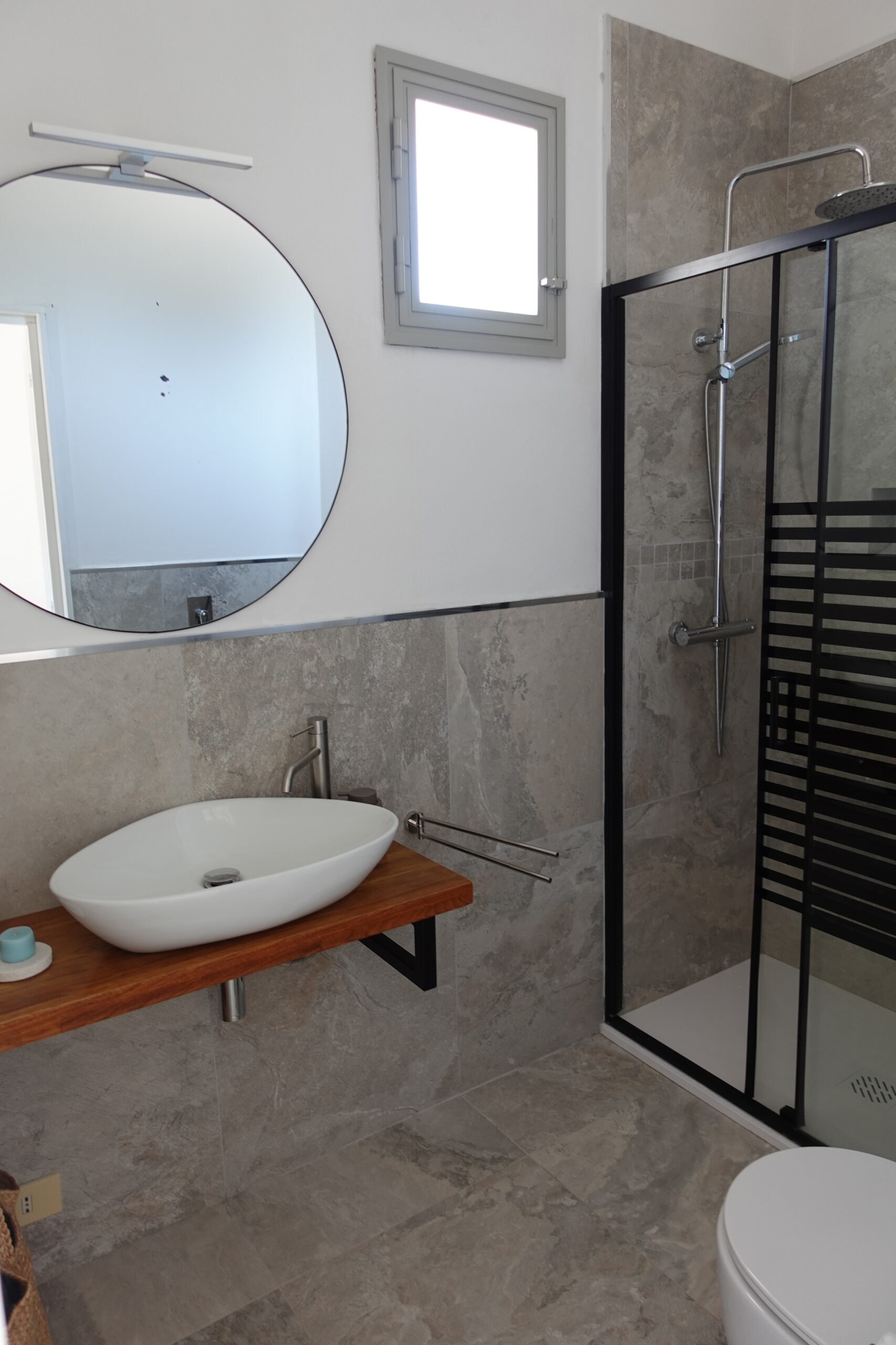 Dettaglio del lavello di Mae a Favignana con dispenser in vetro ambrato e spazzola in legno su piastrelle chiare.