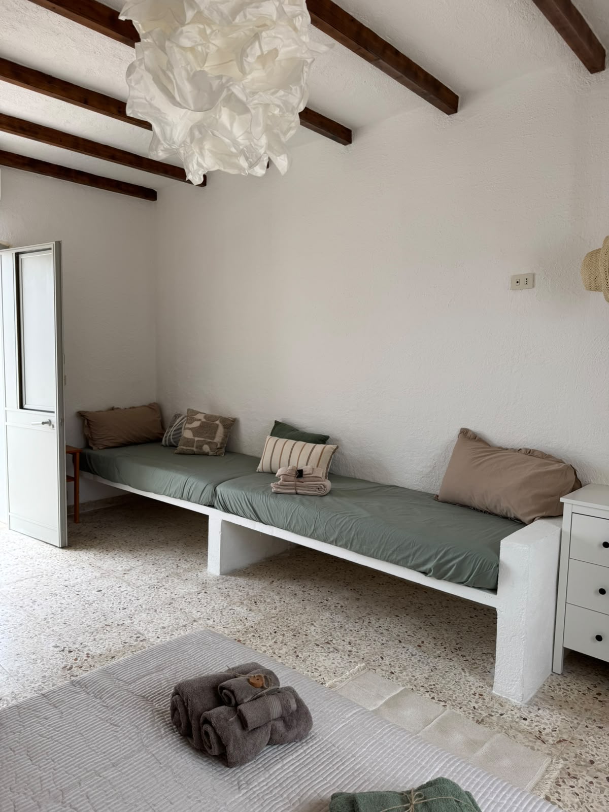 Dettaglio del lavello di Mae a Favignana con dispenser in vetro ambrato e spazzola in legno su piastrelle chiare.