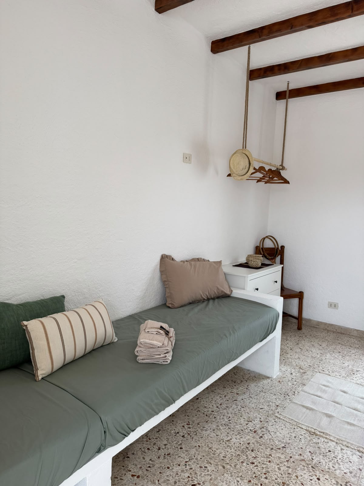 Dettaglio del lavello di Mae a Favignana con dispenser in vetro ambrato e spazzola in legno su piastrelle chiare.