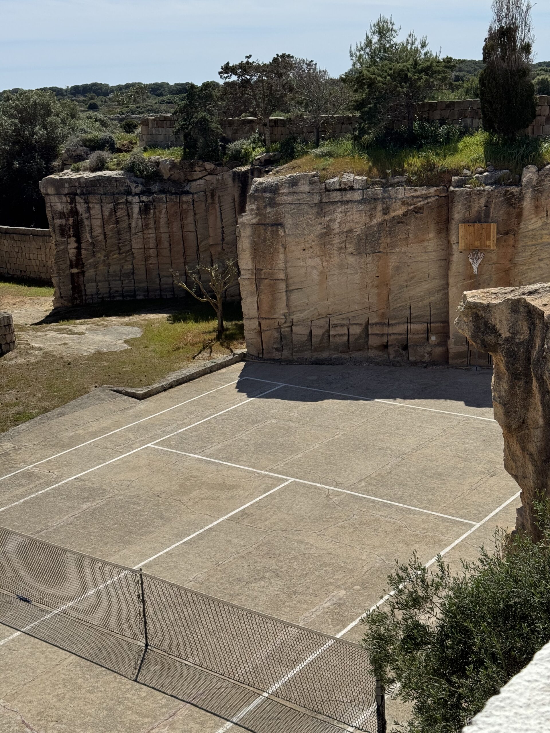 Angolo relax negli esterni di Mae a Favignana con amaca tra gli alberi, affaccio sulla cava di tufo e campo da tennis.