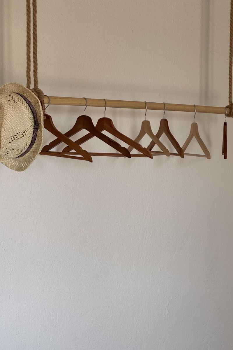 dettaglio di appendiabiti in legno con cappello di paglia appoggiato