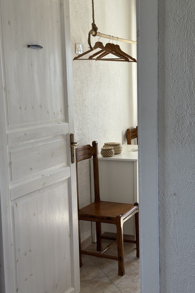 scorcio di una stanza vista da fuori con la porta semi aperta, dalla quale si intravede una sedia in legno e appendiabiti