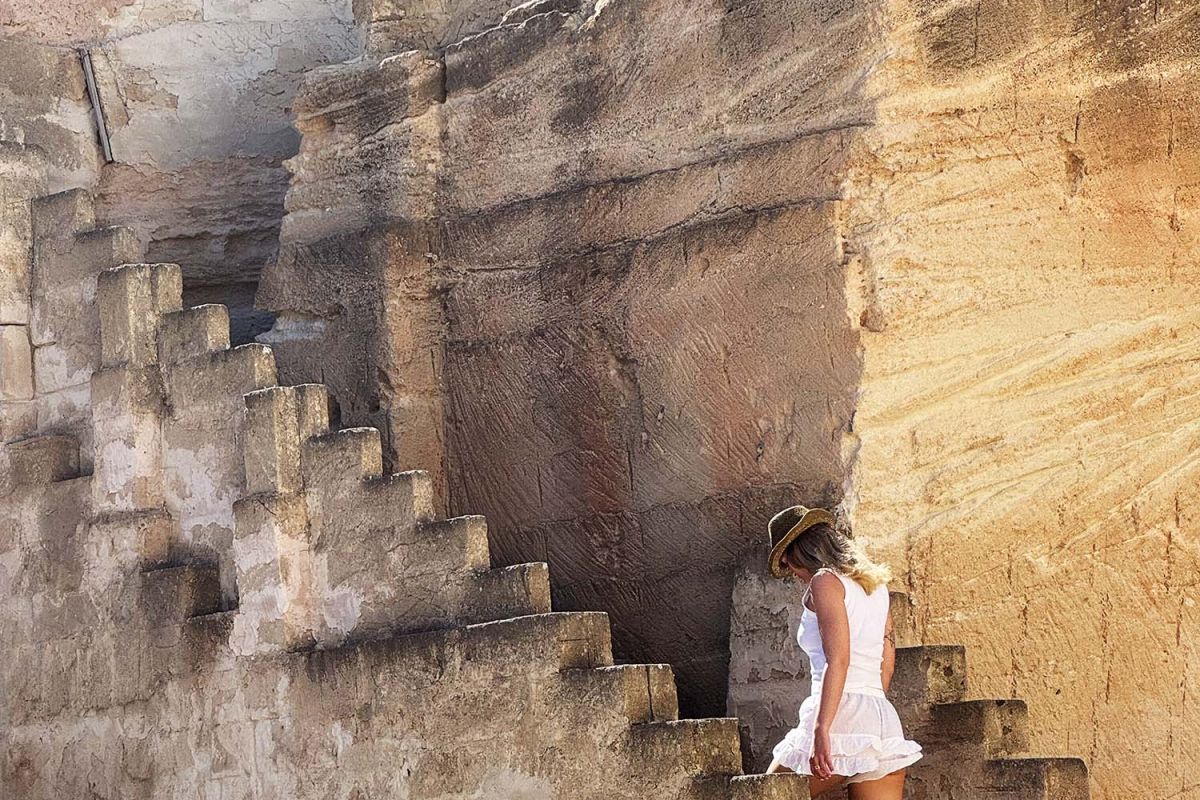 Scorcio della cava di tufo di Mae a Favignana con scale in pietra e una ragazza con cappello le attraversa